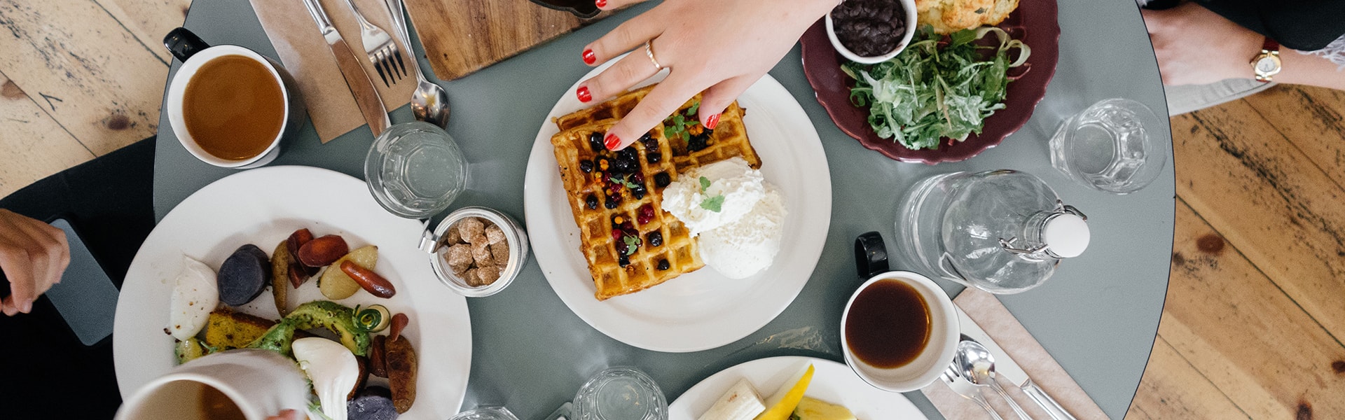 Reich gedeckter Brunch-Tisch von oben mit Waffeln, Kaffee und vielen Tellern