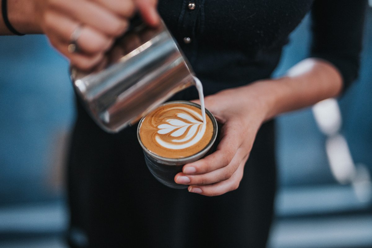 Barista gießt Latte Art in eine Cappuccino-Tasse